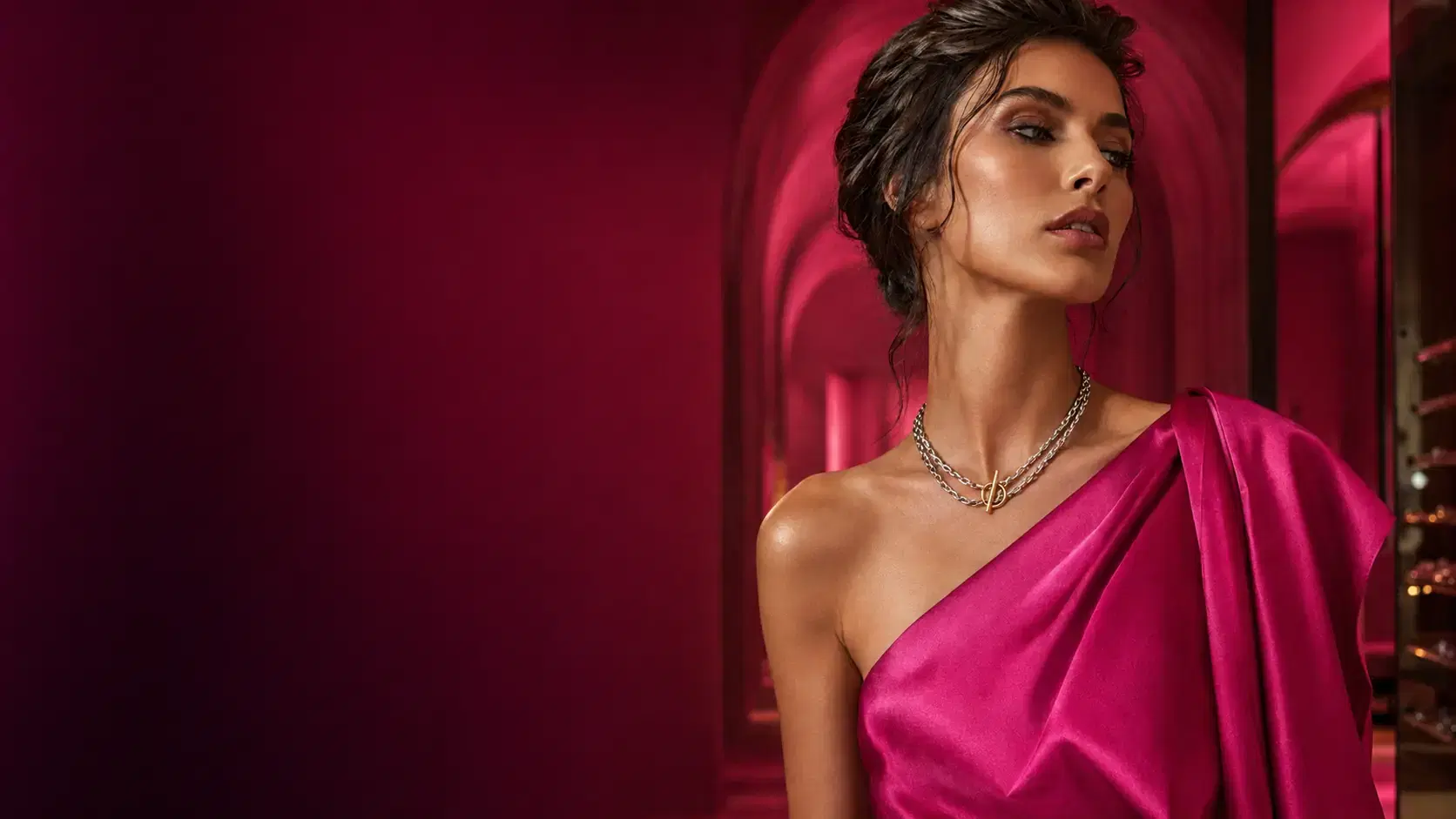 Editorial luxury fashion portrait — a model in an asymmetric gown wearing fine jewellery.
